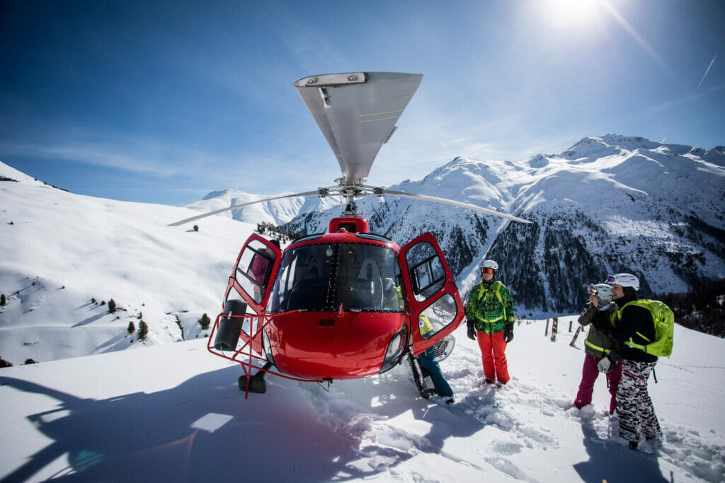 Skiers take a break next to helicopter in the Alps of Livigno