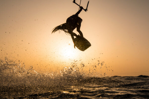Kitesurferin beim Springen mit Sonnenuntergang in Trianda