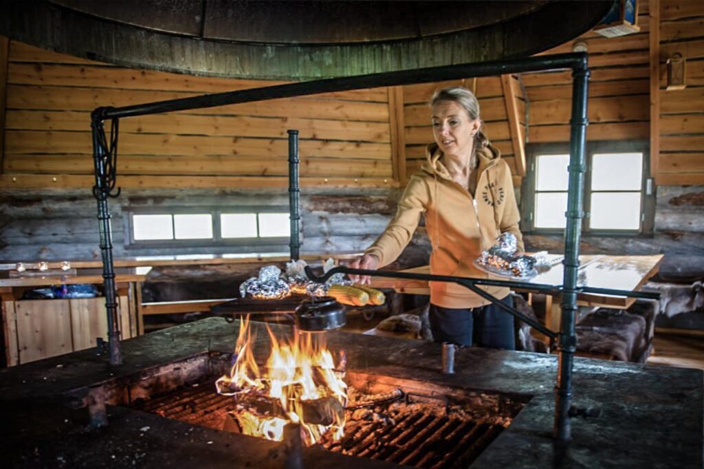Frau kocht über offenem Feuer in Lappland