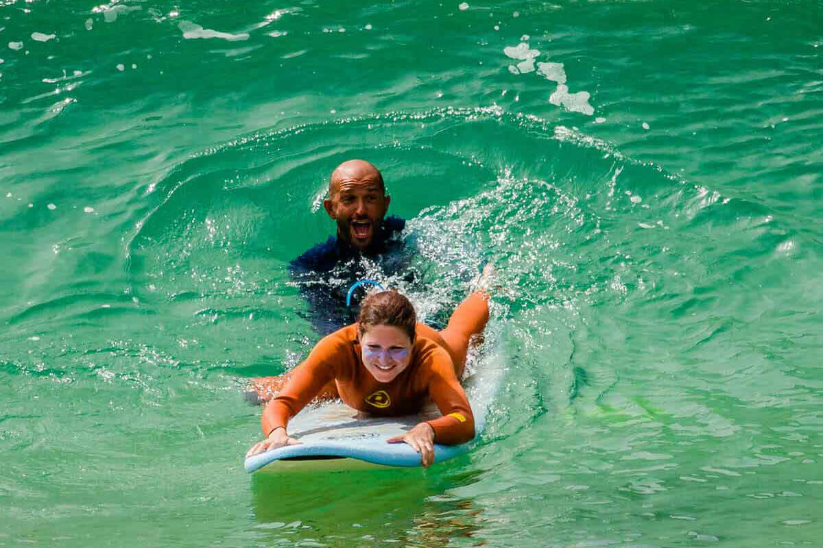 Teacher teaches student how to surf at surf camp