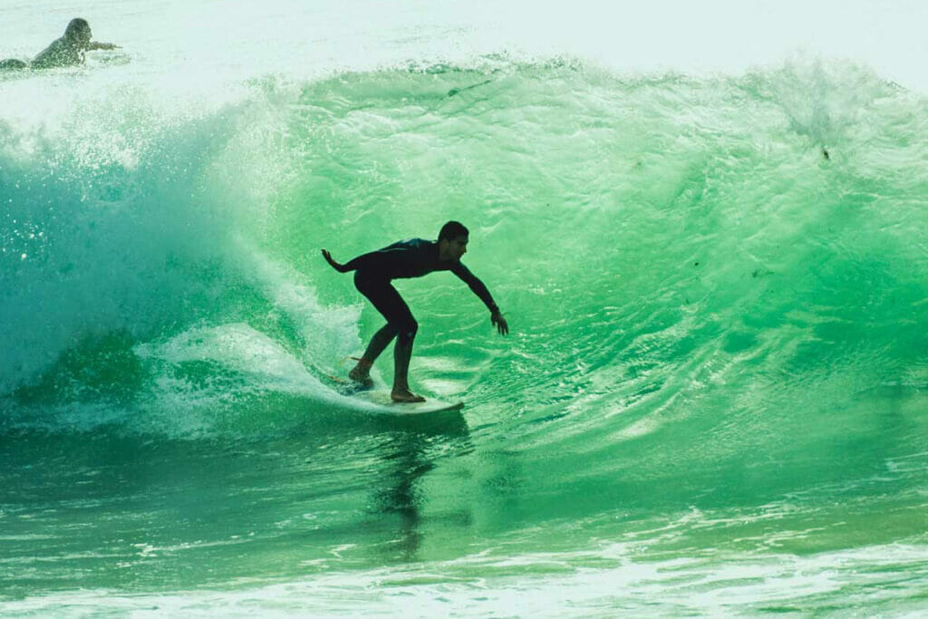 Surfer steht am Board unter einer Welle in Portugal