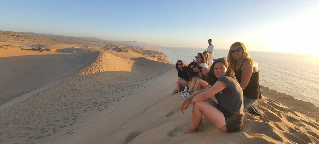 Women group on dune at sunset, Morocco