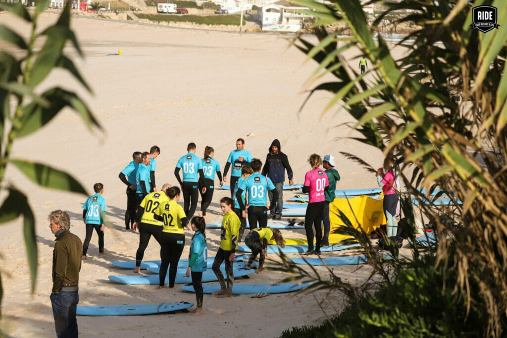 Surfkurs-Gruppe,Surfboards,Strand,blaue,gelbe,pinke Lycras,Bambus im Vordergrund