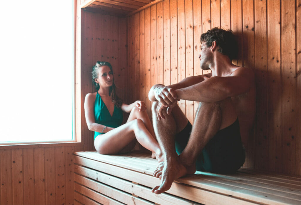 Frau und Mann in Sauna,Frau bekleidet mit grünem Badeanzug, Mann bekleidet mit Shorts